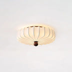 This Clérachic ceiling light sits close to a pale ceiling, its pleated shade glowing and a walnut-colour finial at the centre.