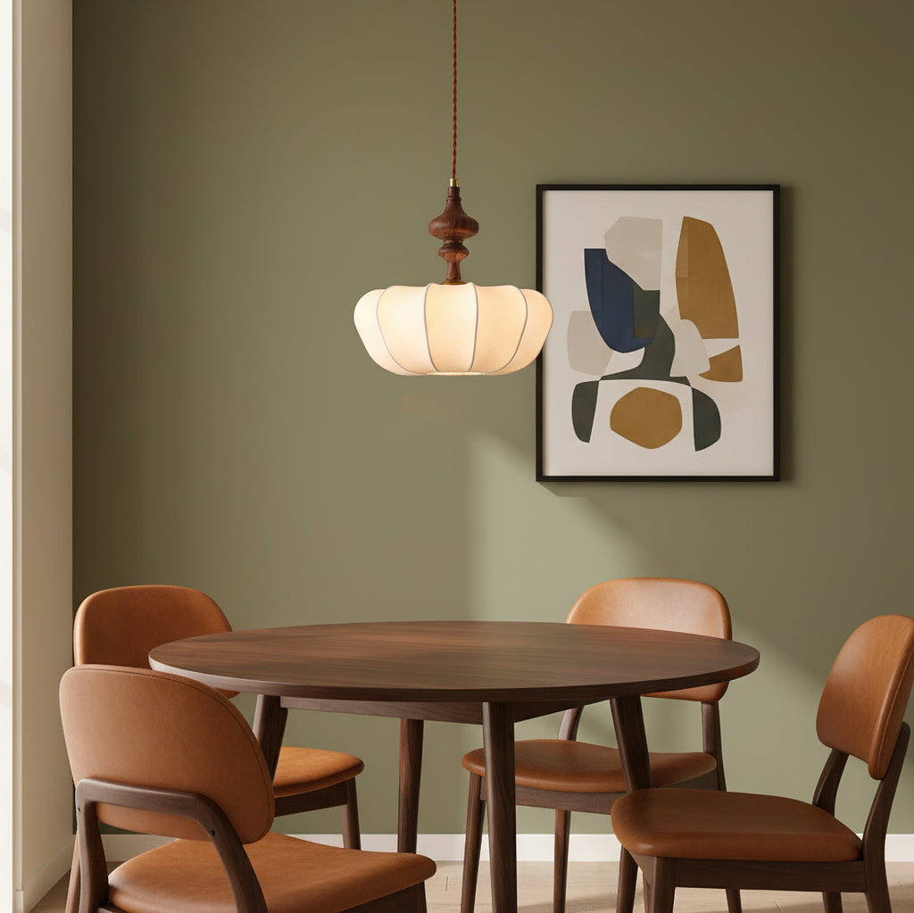 Above a round wooden dining table with tan chairs, this Clérachic pendant hangs against a sage-green wall with abstract art.