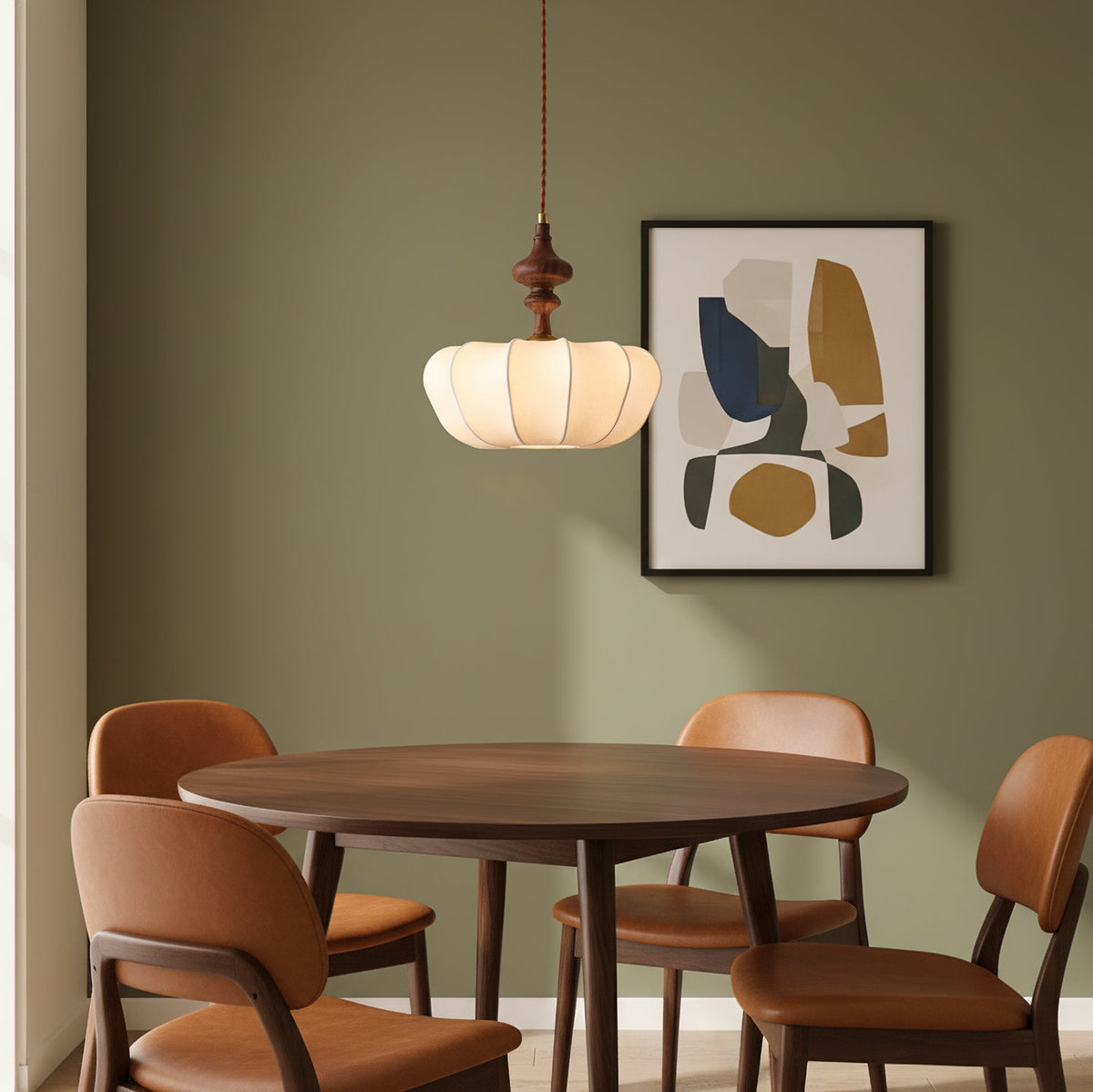 Above a round wooden dining table with tan chairs, this Clérachic pendant hangs against a sage-green wall with abstract art.