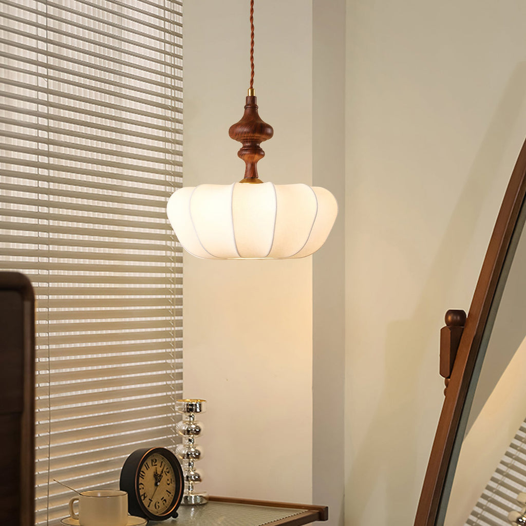 Ribbed white silk shade of a Clérachic pendant glowing in a corner beside slatted blinds, with a small clock below.