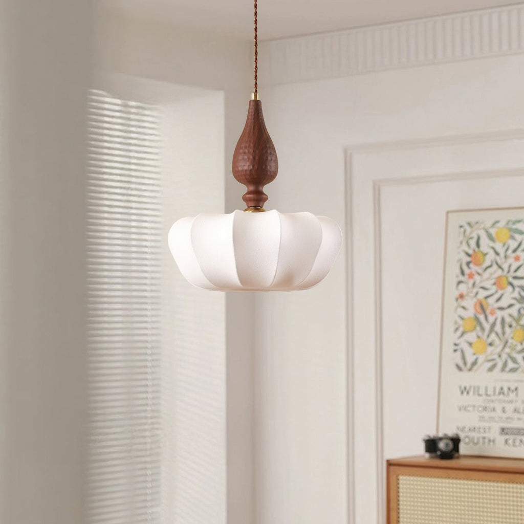 This Clérachic pendant with a wide scalloped shade hangs in a bright room beside a framed print and a rattan-front cabinet.