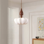 This Clérachic pendant with a wide scalloped shade hangs in a bright room beside a framed print and a rattan-front cabinet.