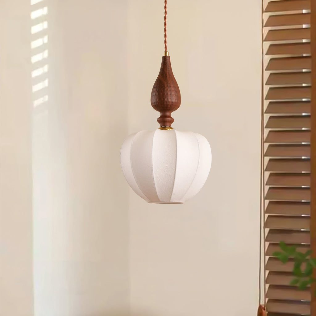 An unlit Clérachic pendant with a rounded white shade and a dark wooden top, next to wooden louvred shutters.