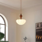 Clérachic pendant lit against an arched window and wall panelling, seen from below to show the glowing underside of the shade.
