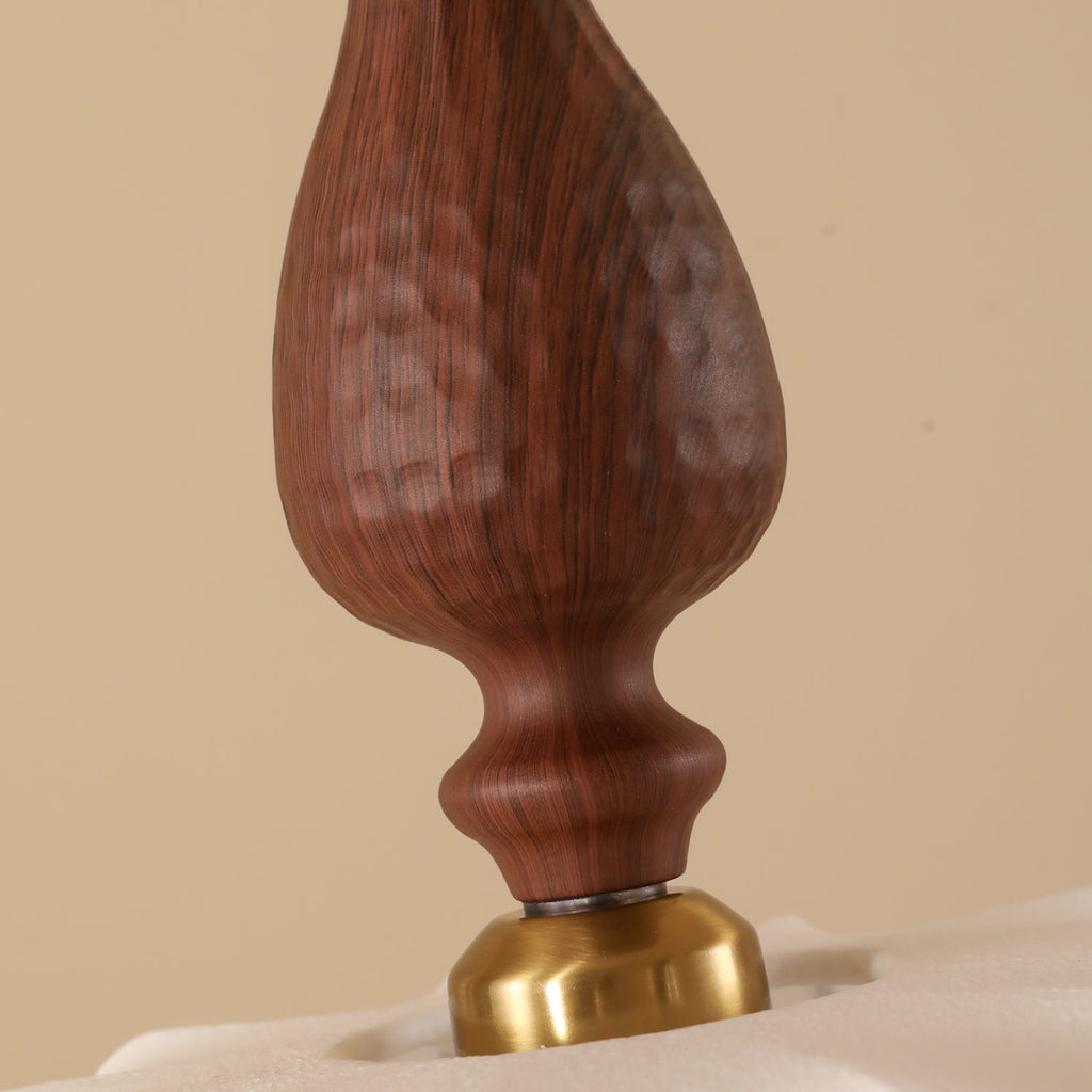 Close view of the carved wood grain on the top of this Clérachic pendant, resting on a brass cap over a pale fabric surface.