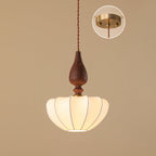 Wide, flatter shade on a Clérachic pendant with a wooden top, on a tan backdrop with the brass ceiling plate shown in an inset.