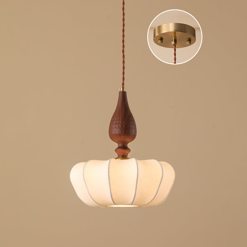 Compact wide shade on this Clérachic pendant, lit from below, with an inset of the brass ceiling plate on a tan backdrop.