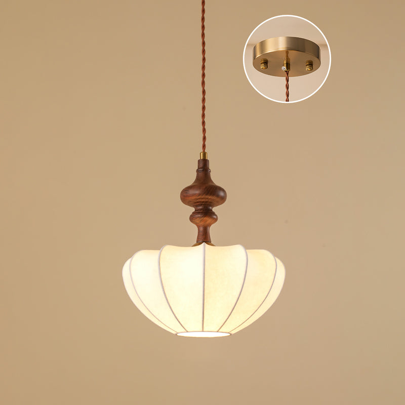 A Clérachic pendant with a broad, shallow white shade and a turned wooden top, lit underneath, with the ceiling plate in an inset.