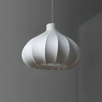 Clérachic garlic-bulb silk pendant light unlit against a dark grey backdrop, its matte white lobes overlapping like petals along the hem.