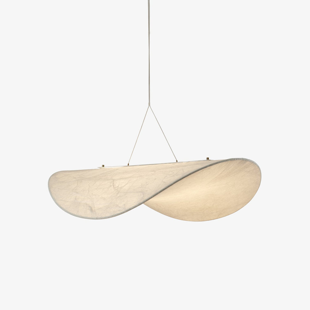 A white, softly twisted, leaf-shaped pendant hangs from two fine cables against a plain pale backdrop, shown as this Clérachic silk pendant.