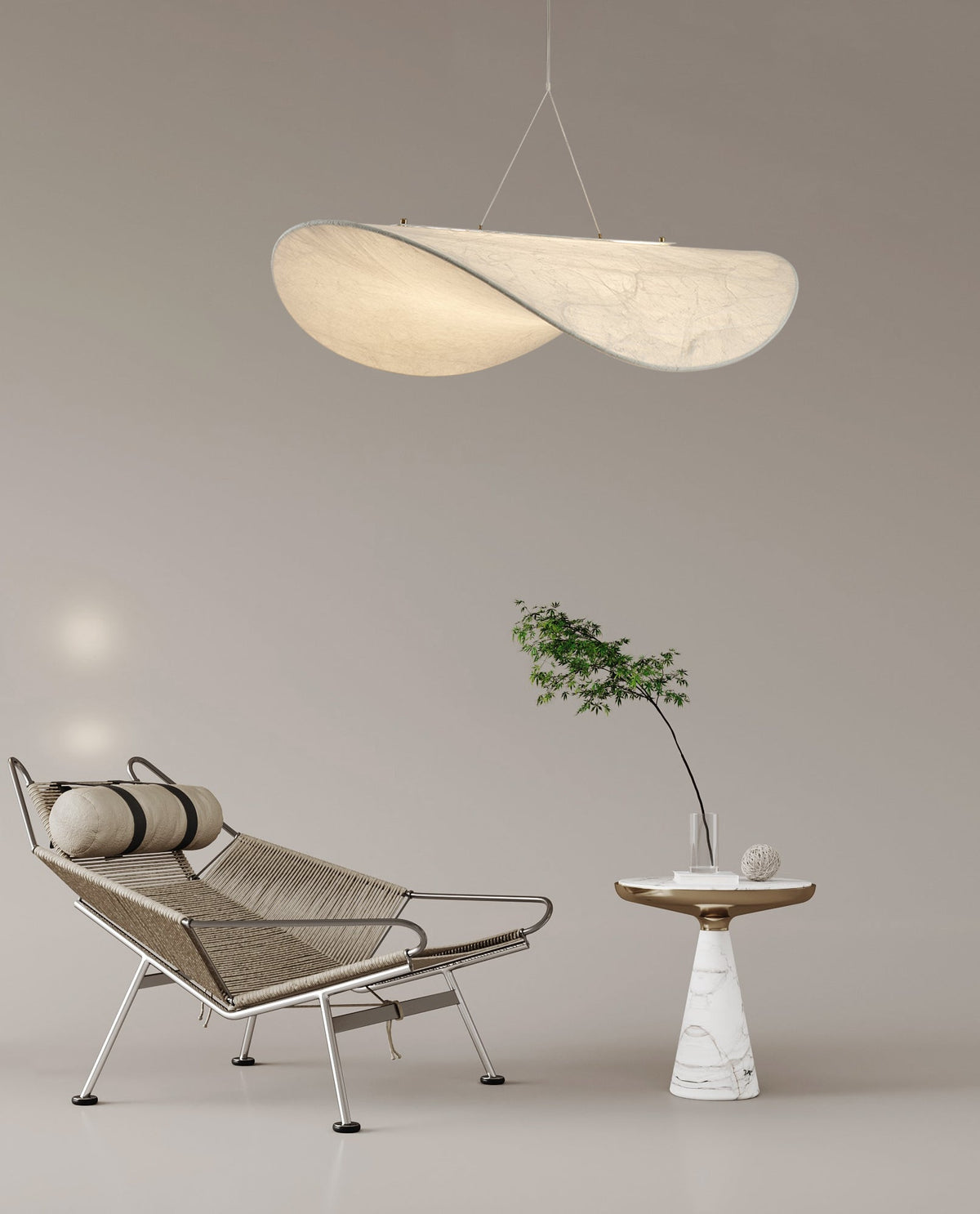 A twisted white pendant hangs in a taupe room above a wire lounge chair and a small marble side table with a green branch, from Clérachic.