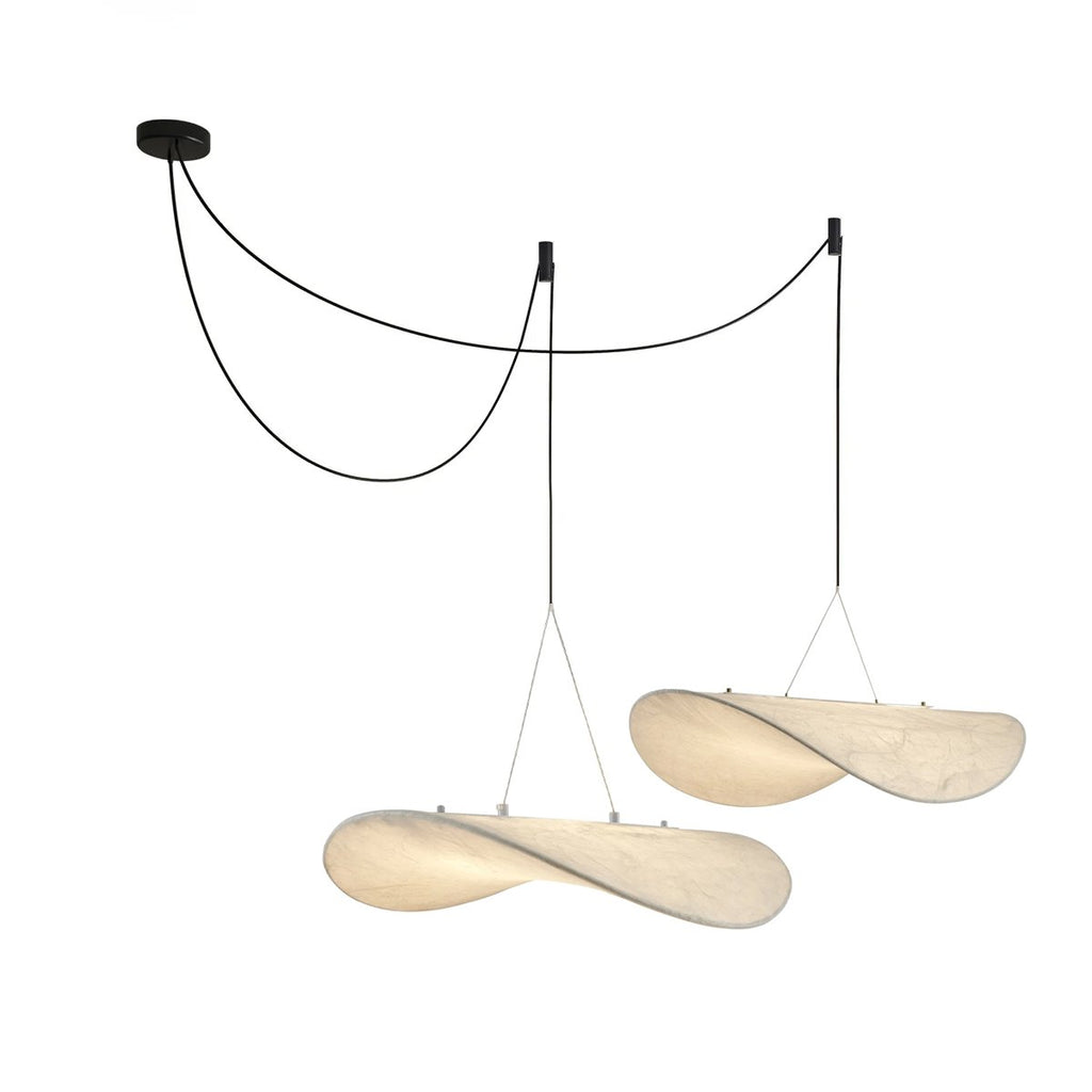Two twisted white pendants hang from a black ceiling canopy on looped black cables, shown on a white backdrop, from Clérachic.