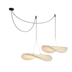 Two twisted white pendants hang from a black ceiling canopy on looped black cables, shown on a white backdrop, from Clérachic.