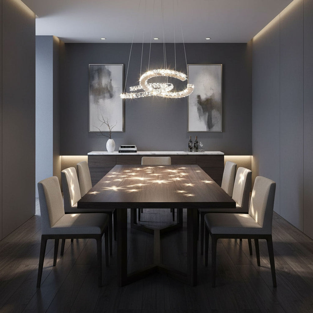 Crystal crescent pendant from Clérachic above a dark dining table, with spots of light scattered across the table top.