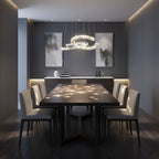 Crystal crescent pendant from Clérachic above a dark dining table, with spots of light scattered across the table top.