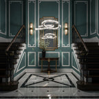 Clérachic crescent pendant in a teal panelled stairwell with a curved double staircase, a round console and a gilt mirror.