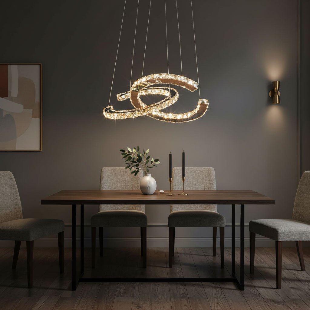 Clérachic crescent pendant glowing warm above a wooden dining table with fabric chairs, a vase and two candles.