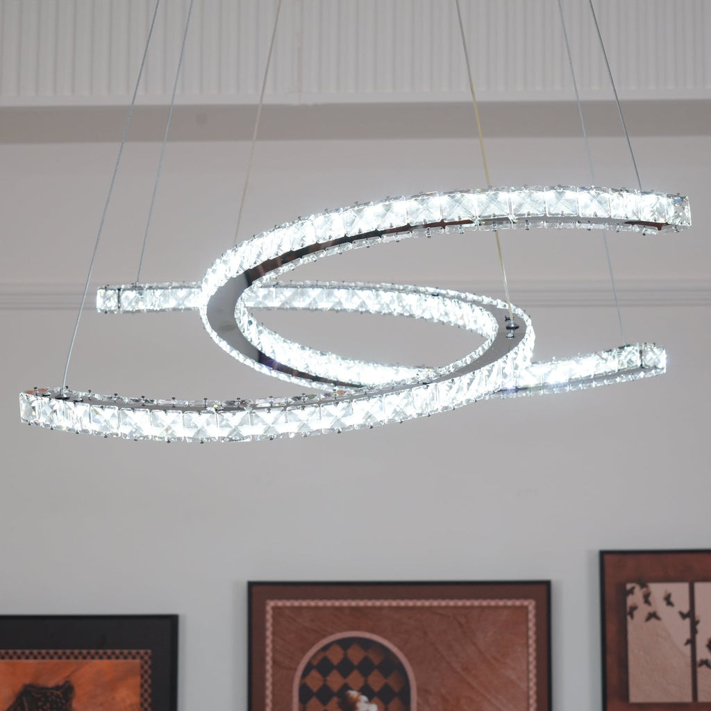 Clérachic crystal pendant lit in a bright white tone, seen from a low angle in front of a panelled wall.