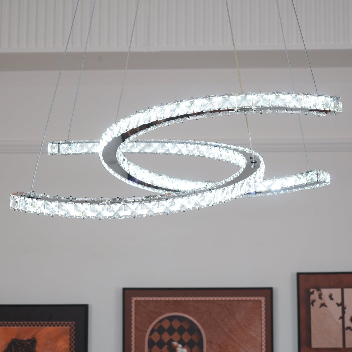 Clérachic crystal pendant lit in a bright white tone, seen from a low angle in front of a panelled wall.