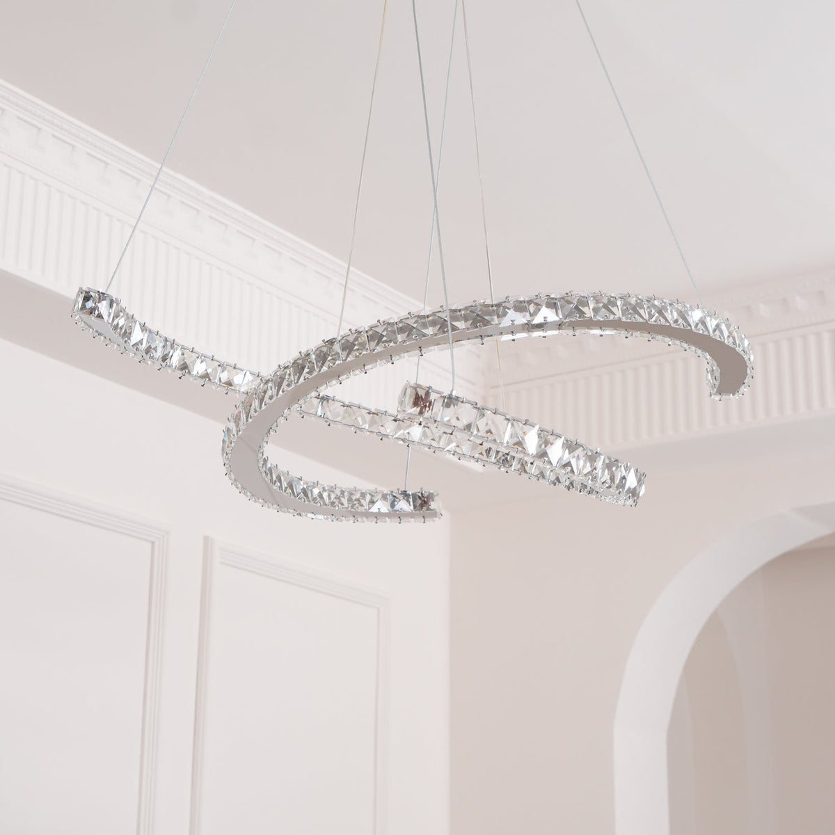 Unlit Clérachic crystal pendant seen from below, its two steel crescents catching light beside an arched doorway.