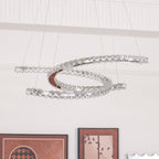 Unlit Clérachic crystal pendant in front of a white wall, with framed pictures along the bottom of the frame.