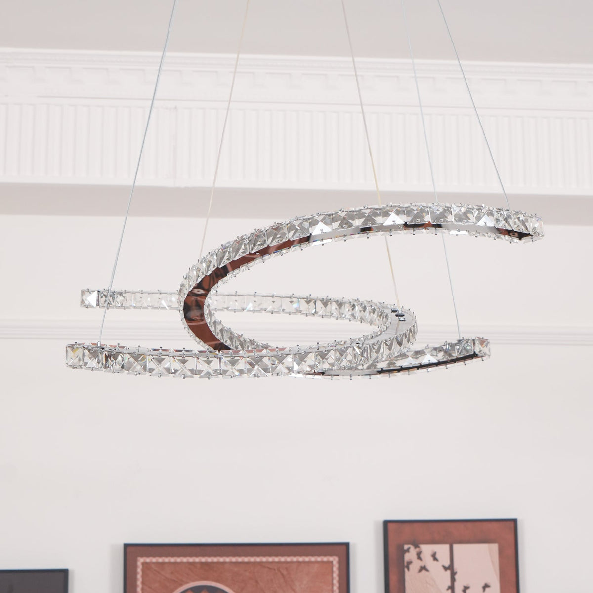 Clérachic crescent pendant unlit, its faceted crystals and mirror-polished steel clear against a white panelled wall.
