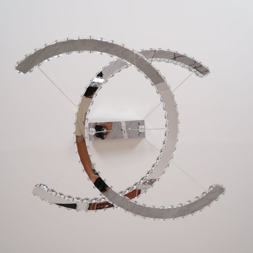 View from underneath the Clérachic pendant, showing the polished steel back of the two crescents and the ceiling plate.