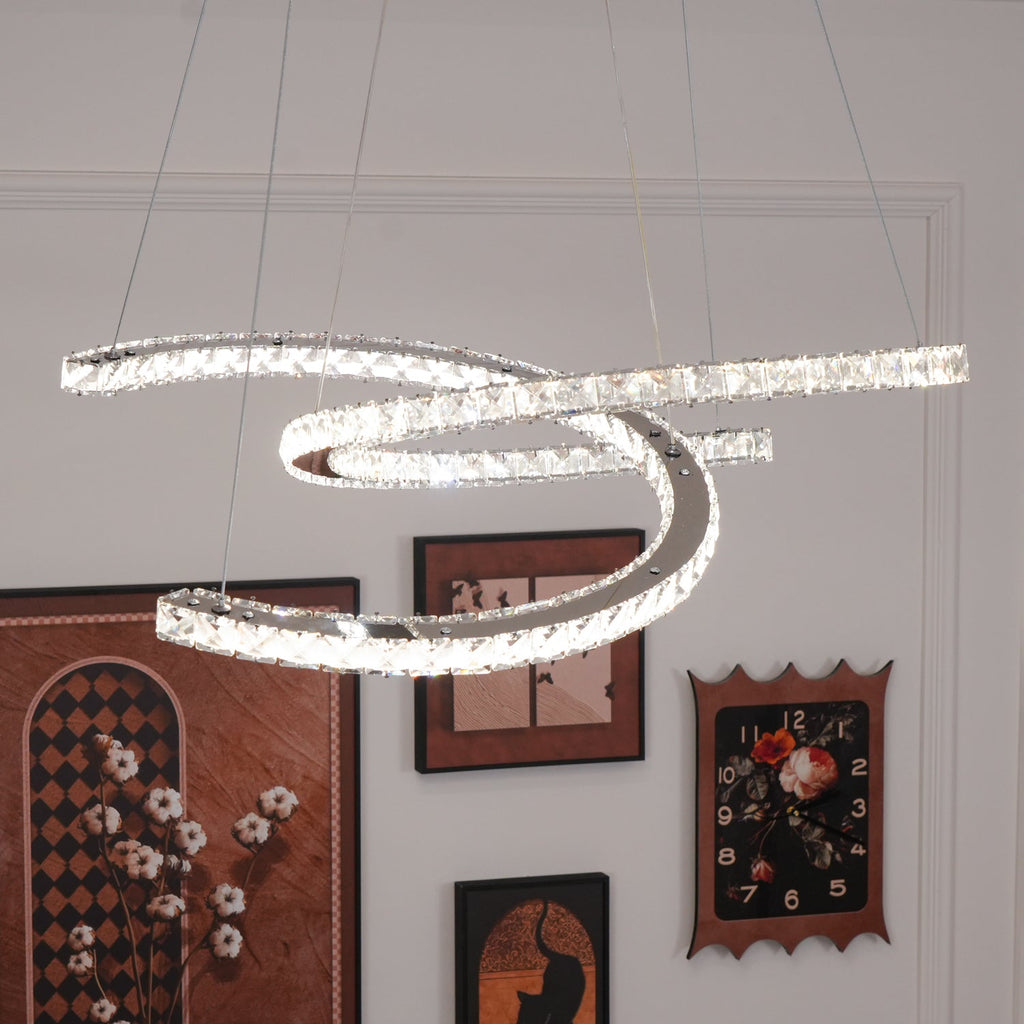 Lit Clérachic pendant close to the camera, with framed pictures and a clock on the white wall beneath.