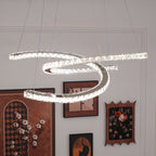 Lit Clérachic pendant close to the camera, with framed pictures and a clock on the white wall beneath.