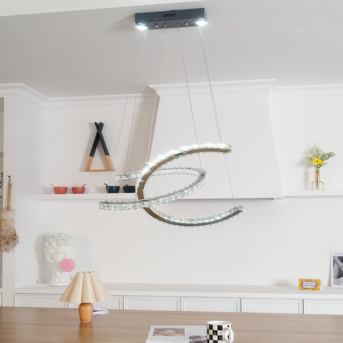 Clérachic pendant lit cool white beneath its dark canopy, with a fluted table lamp and shelf decor behind.