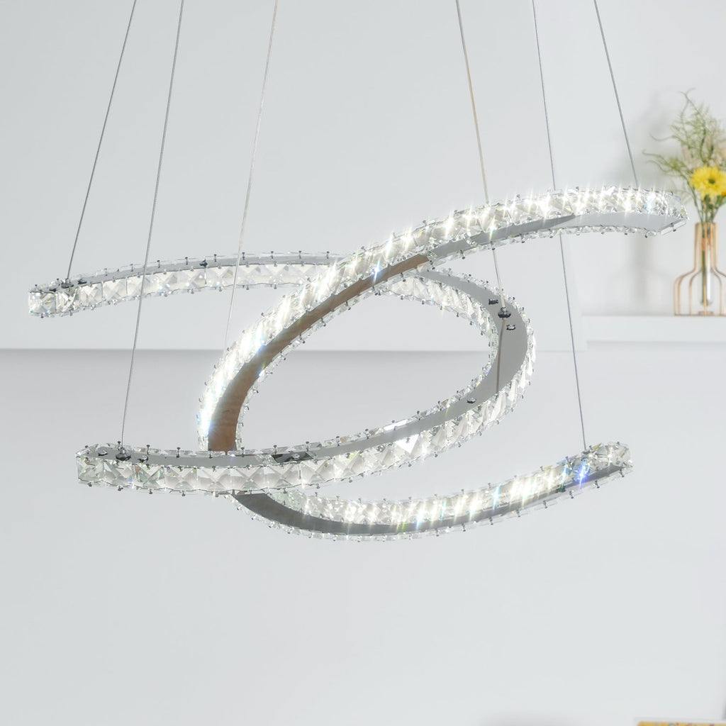 Close, upward view of the Clérachic pendant lit, its crystal-edged crescents crossing against a pale wall.