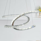 Close, upward view of the Clérachic pendant lit, its crystal-edged crescents crossing against a pale wall.