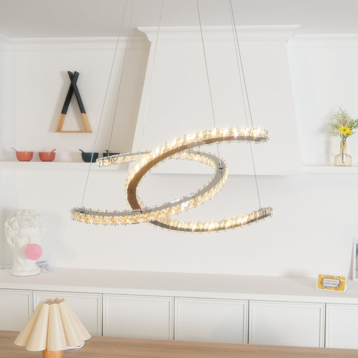 Warm-lit Clérachic pendant with cognac-toned crystals, with the dark canopy and a plaster bust in the white room.