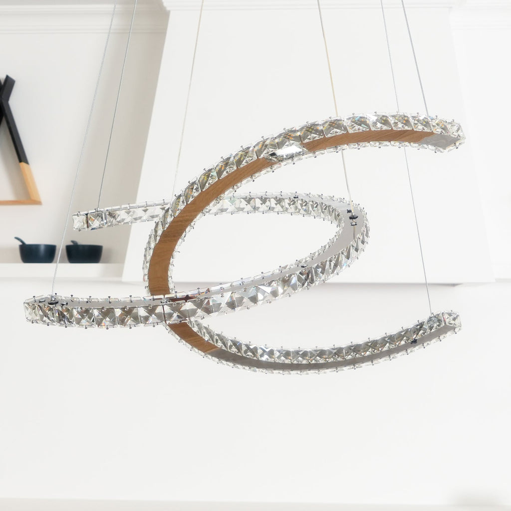 Unlit Clérachic pendant seen up close, the faceted crystal rims and brown-toned inner band visible against a white wall.