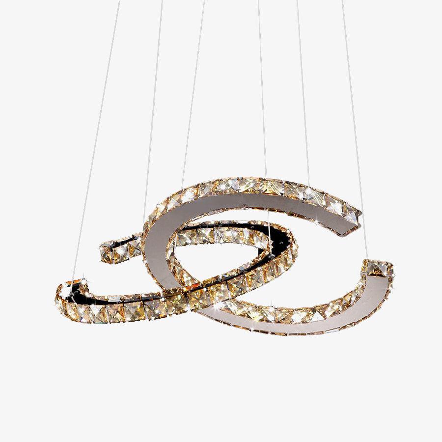 Clérachic crystal pendant with cognac-toned stones, lit and hanging from thin cables on a plain pale backdrop.
