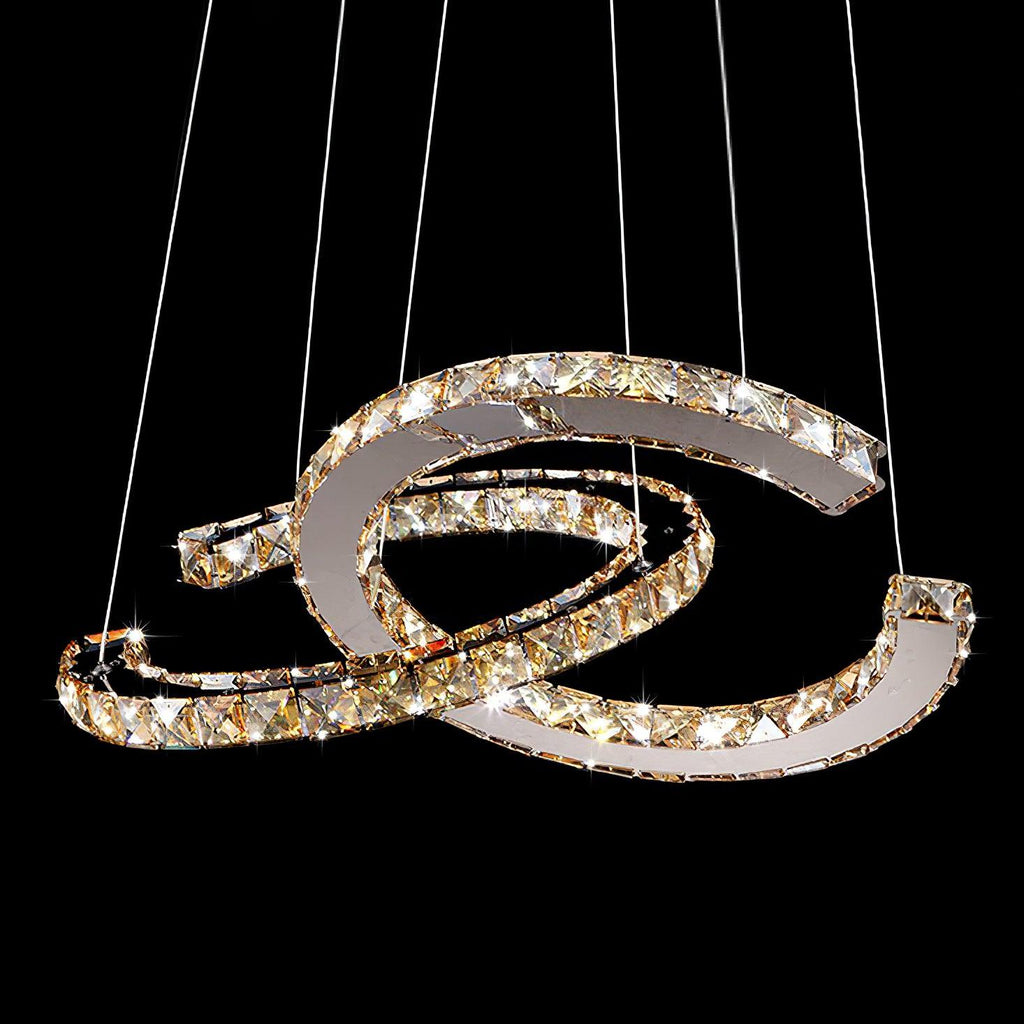 Cognac-toned Clérachic crystal pendant lit against black, its facets sparkling on the two crescents.