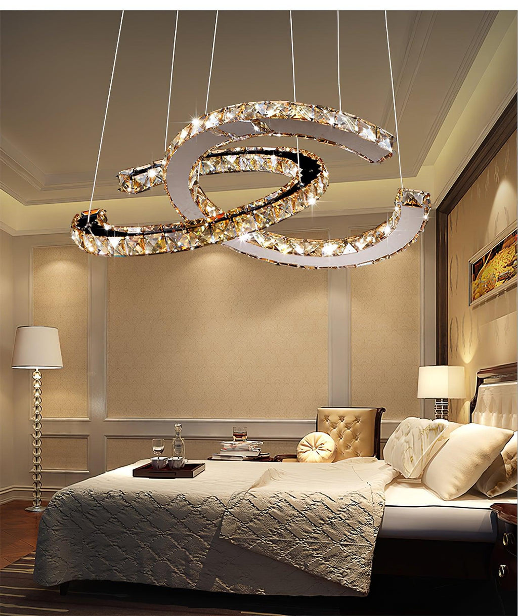 Clérachic crystal pendant with cognac-toned stones lit above a bed with a quilted cover in a warm beige bedroom.