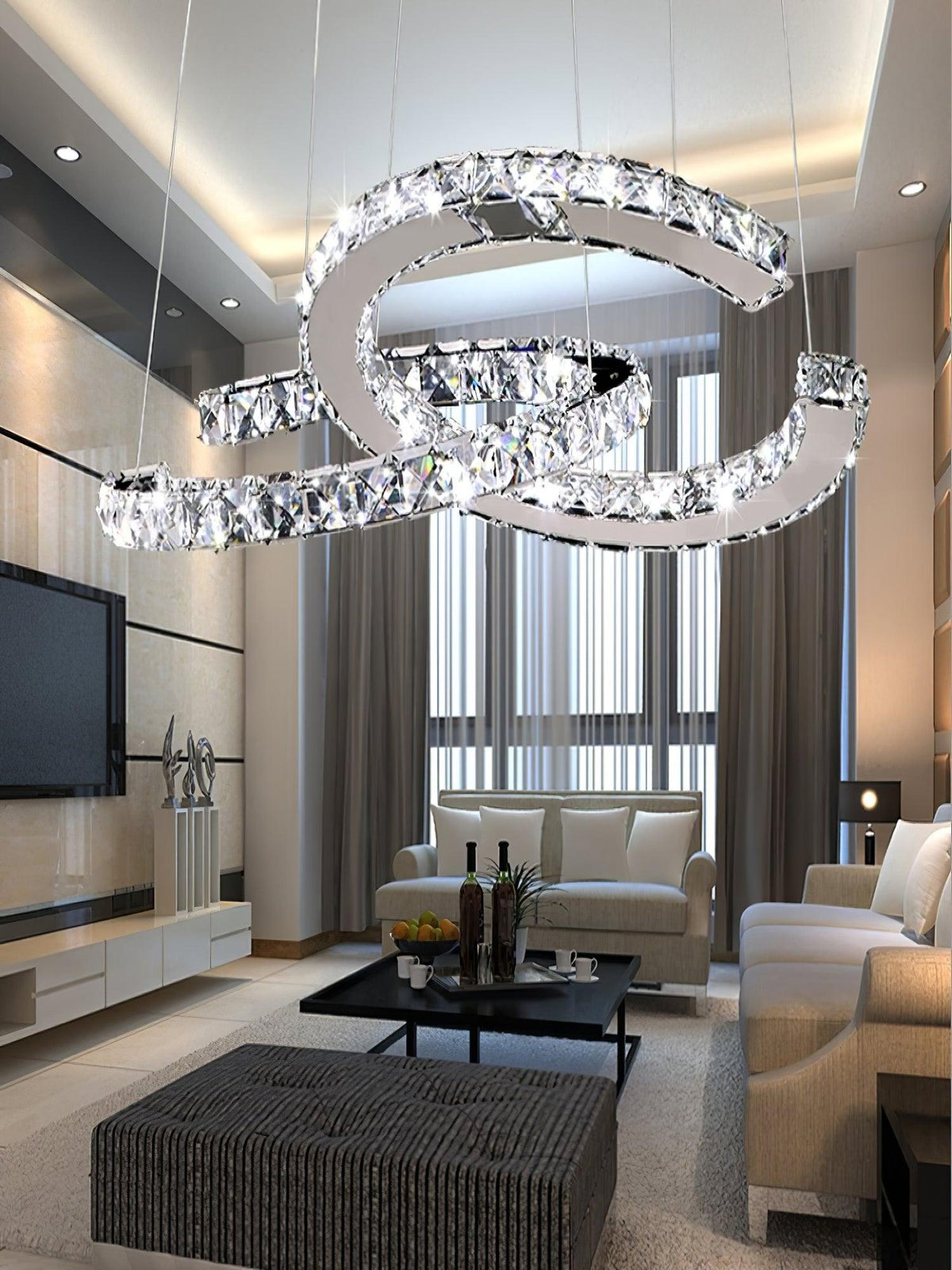 Clérachic crystal pendant lit in a high-ceilinged living room with a television, cream sofas and tall curtains.
