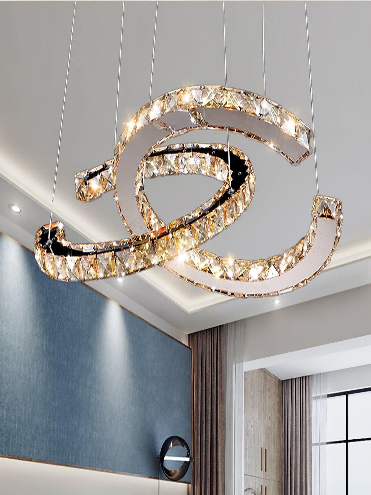 Close, upward view of the cognac-toned Clérachic pendant lit against a ceiling with recessed lights and a blue wall.