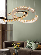 Cognac-toned Clérachic pendant lit beside a sage-green wall, with a brown sofa and a bunch of yellow flowers below.