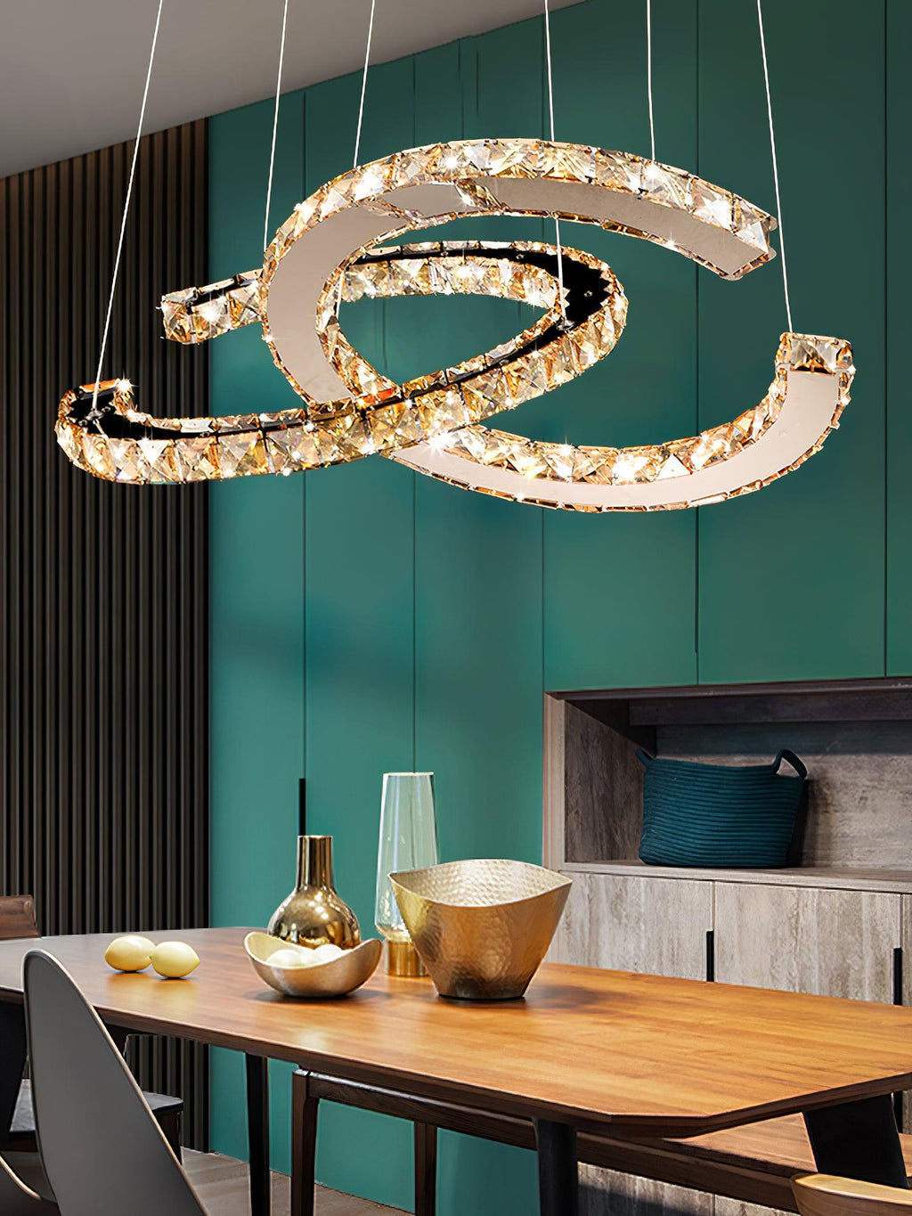 Clérachic crescent pendant with cognac-toned crystals above a wooden table with gold bowls, against a teal wall.