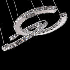 Close view of the clear-crystal Clérachic pendant on black, showing the crossed crescents and the cables that hold them.