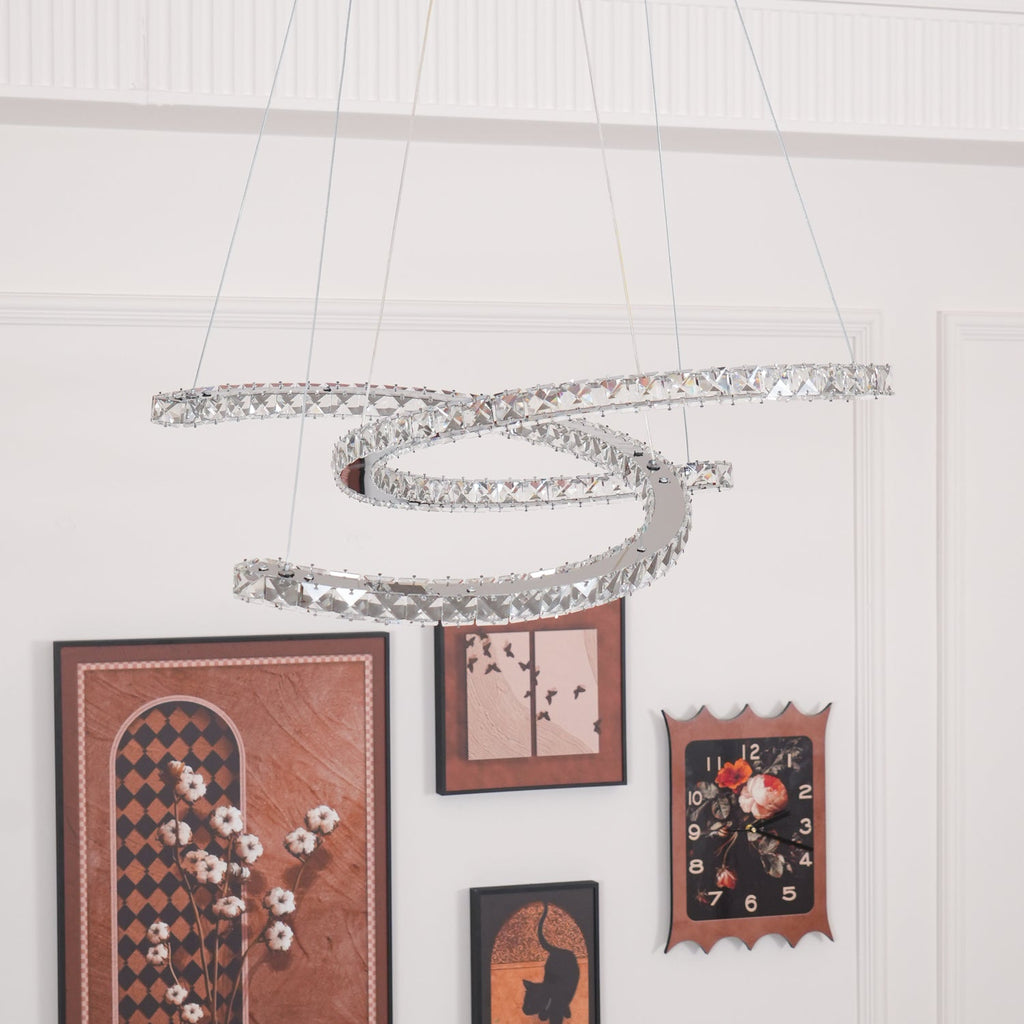 Unlit Clérachic crystal pendant hung low before a white wall with a gallery of framed pictures and a clock.