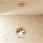 Clérachic champagne glass sphere pendant hangs against a warm plaster ceiling, its Edison bulb glowing inside.