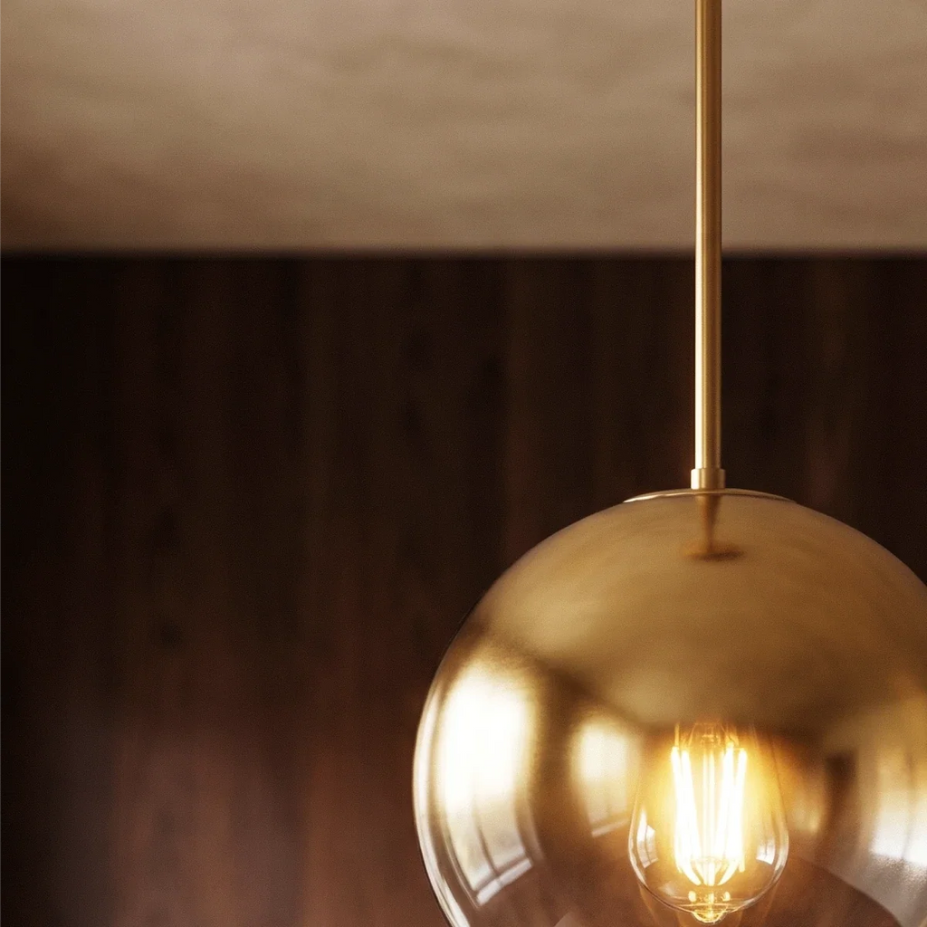 Clérachic close-up frames the champagne metal rod and glass sphere top against a dark wood-panelled wall.