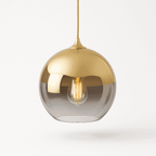 Clérachic pendant light in champagne finish suspended on a slim cord, glass sphere glowing on a white backdrop.
