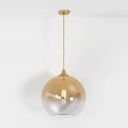 Clérachic champagne-finish pendant hangs full length from ceiling canopy to glass sphere on a plain white ground.