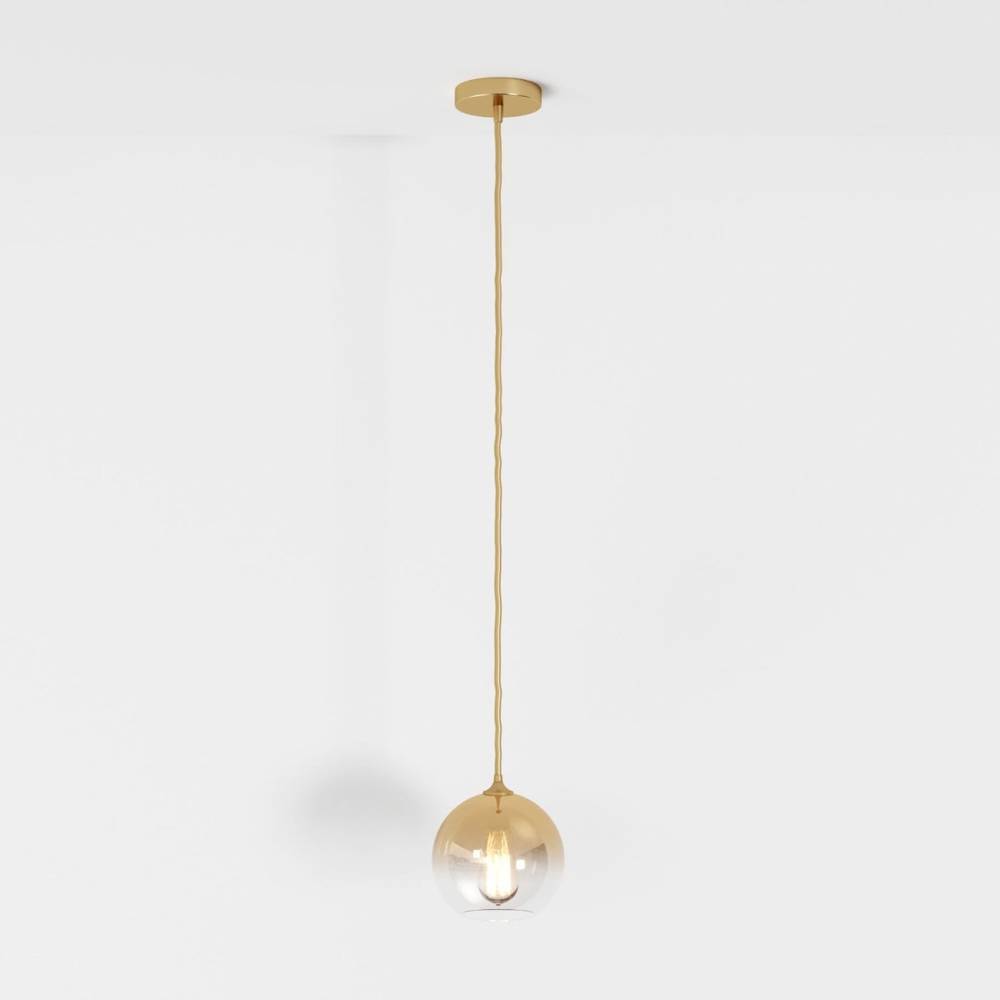 Clérachic gold-toned pendant light shown full drop, glass sphere shade lit from within on a white backdrop.