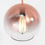 Clérachic extreme close-up of the rose gold gradient glass sphere, filament bulb glowing warm at its centre.
