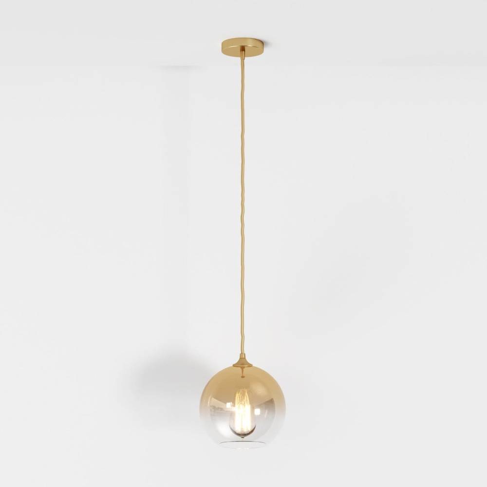 Clérachic champagne pendant light hangs on a matching cord, glass sphere shade lit against a white backdrop.
